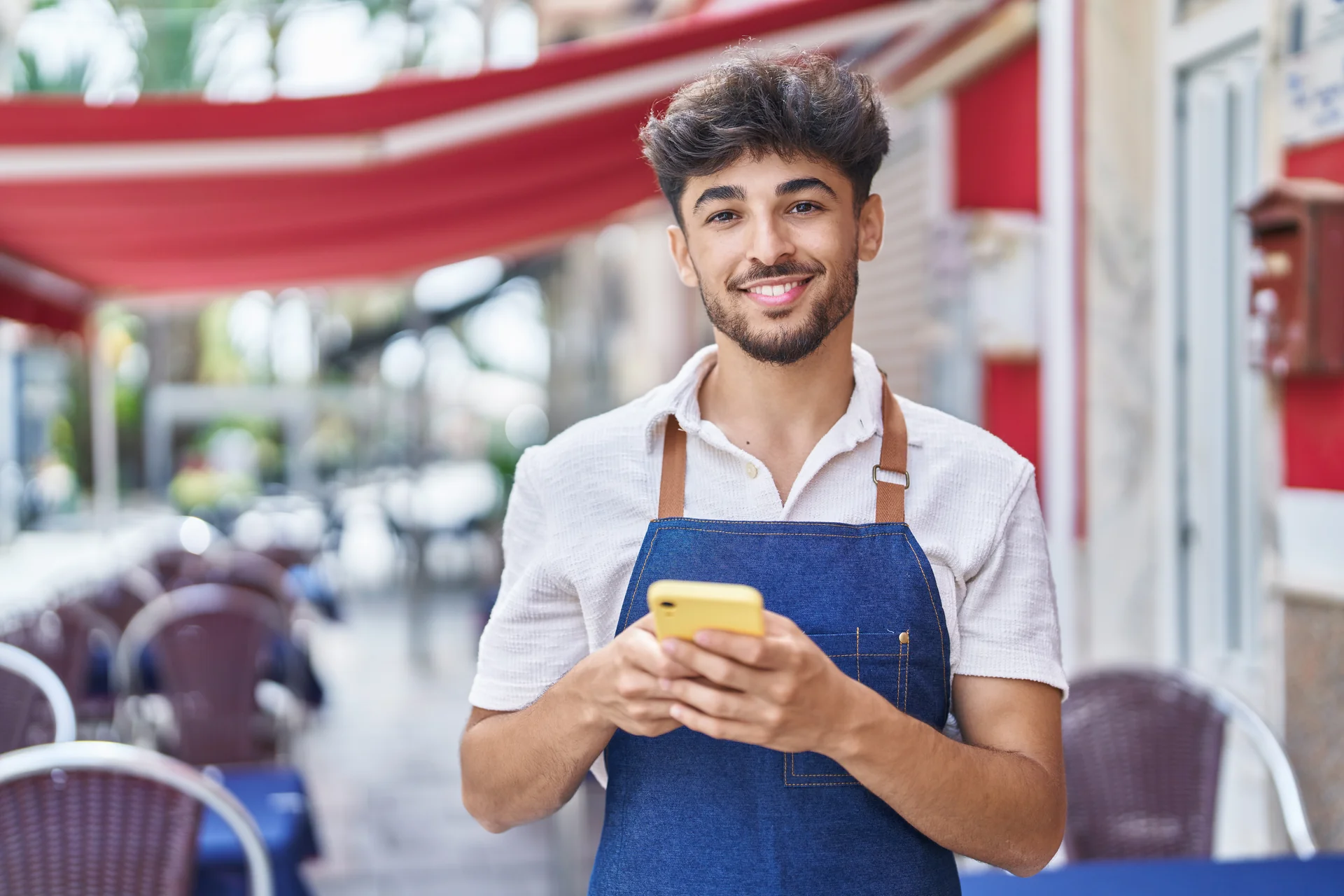 Un addetto alla ristorazione usa il telefono davanti al locale